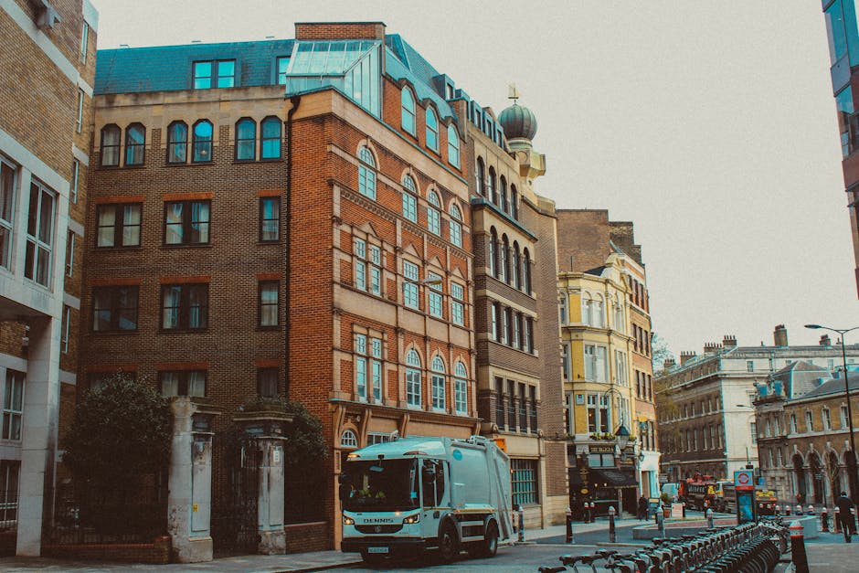 Inside a property, a team of movers from Man With a Van Chelsea is engaged in a home relocation process, with several cardboard boxes and large wrapped furniture pieces prepared for transport. The box